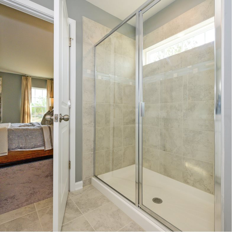 The glass-enclosed shower features a tile surround